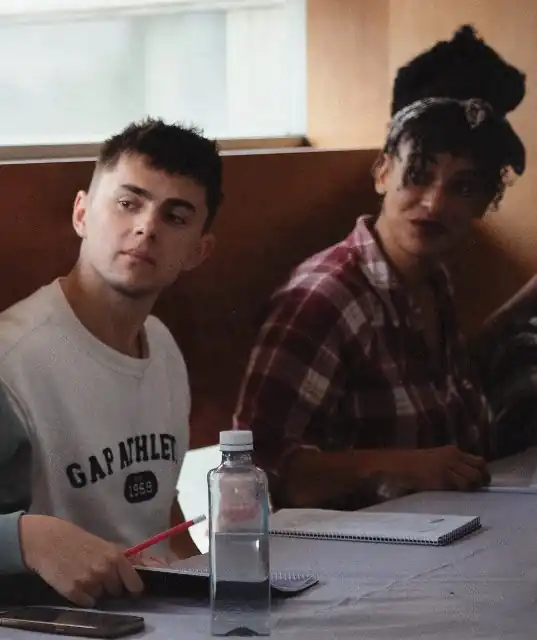 Dos jóvenes conversan sentados a una mesa