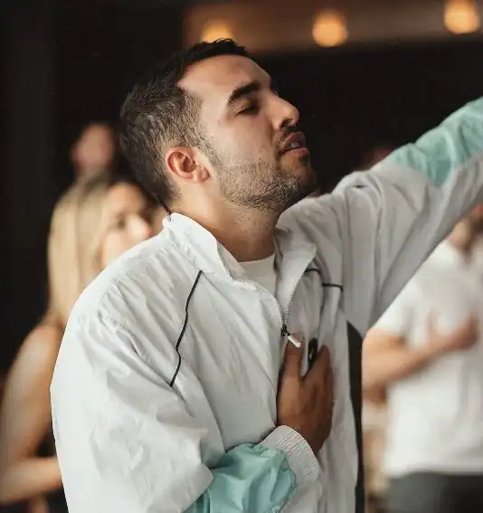 Un joven adora con los ojos cerrados y la mano en el pecho